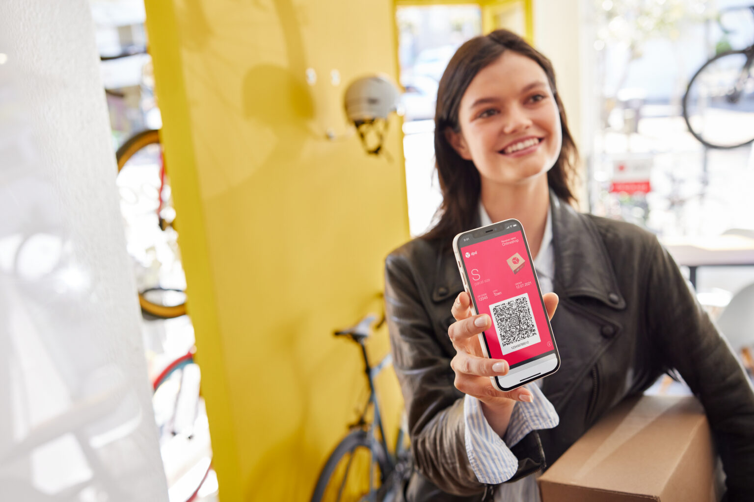 A woman showing a DPD QR code on their phone while handing a parcel to a courier for a quick and easy return
